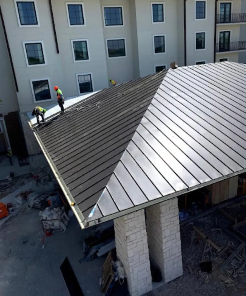 Crew installing standing seam metal roof panels on a commercial project in Spartanburg